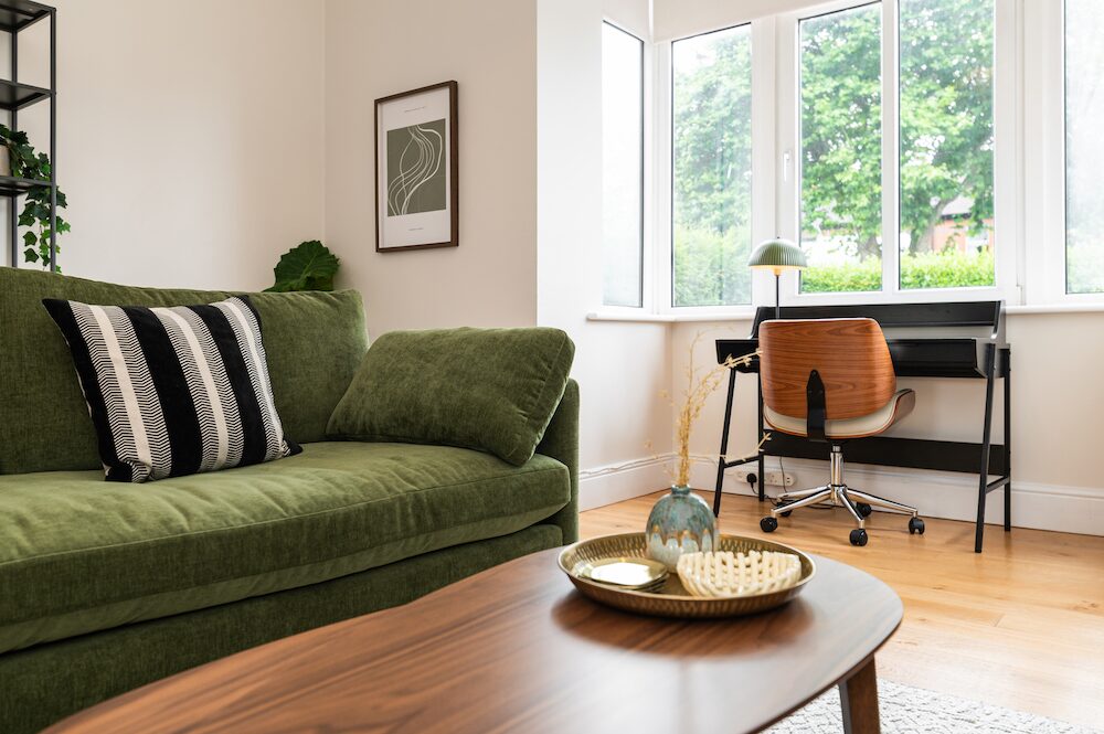 EirStay Donnybrook serviced apartment, Dublin 4 — green velvet sofa, walnut coffee table and dedicated workspace by a bay window onto Morehampton Road