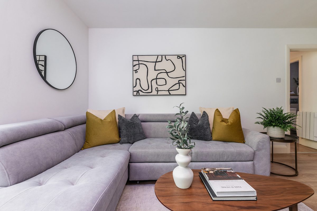 Comfortable living area with corner sofa, round mirror and coffee-table books in EirStay Islandbridge short-term let Dublin 8